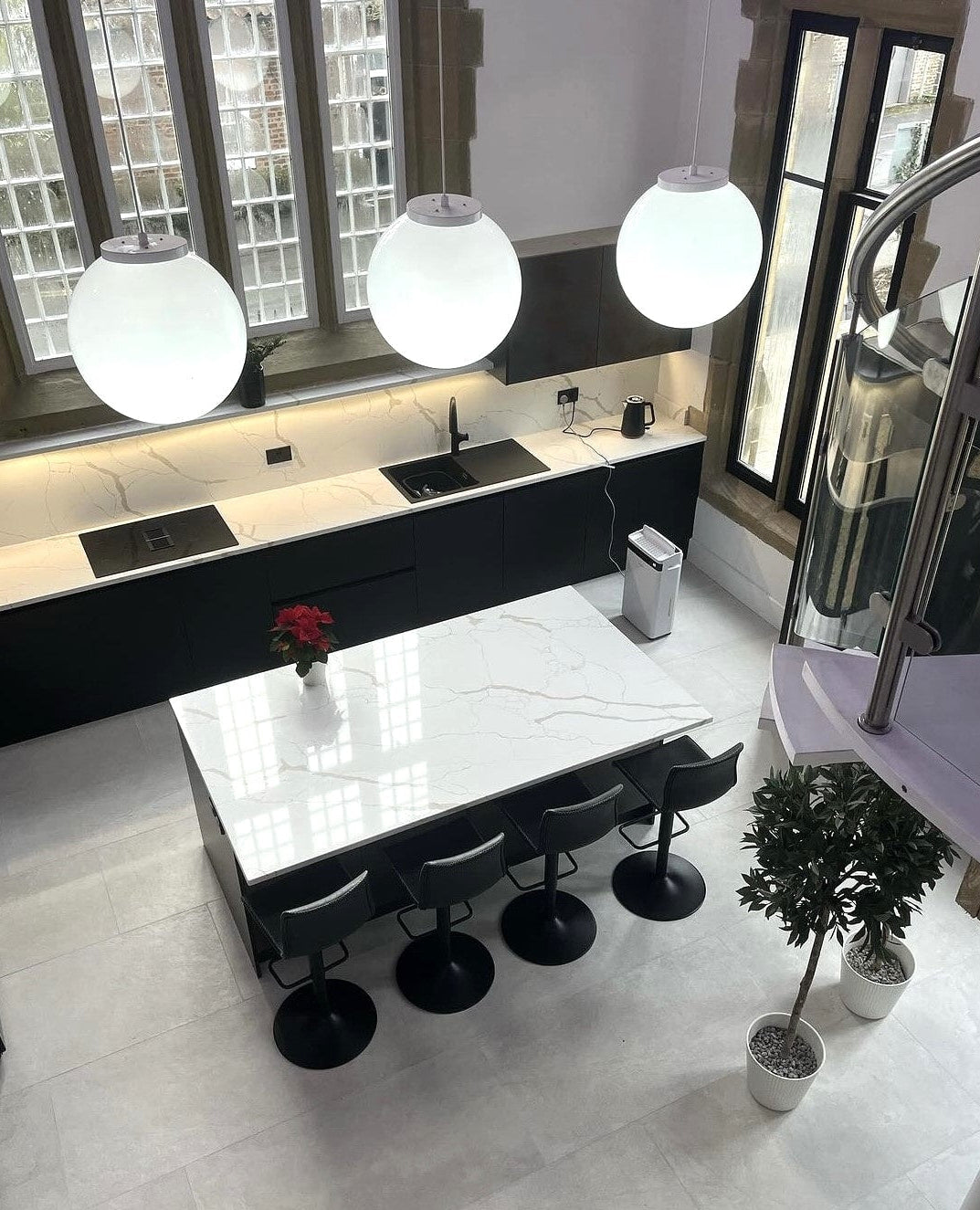 Modern kitchen with white countertops, black appliances, and decorative elements.