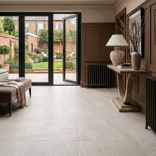 Modern interior with large glass doors leading to a garden, featuring a console table and lamp.