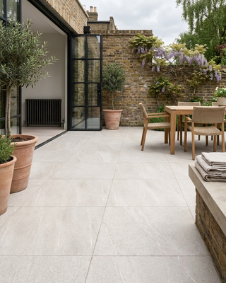 Modern outdoor patio with a dining table, chairs and potted plants.