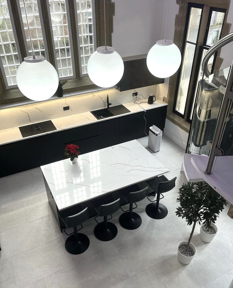 Modern kitchen with white countertops, black appliances, and decorative elements.