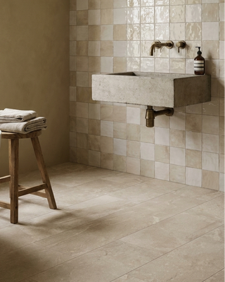 Bathroom with tiled wall, freestanding bathtub, chequered wall and wooden stool.