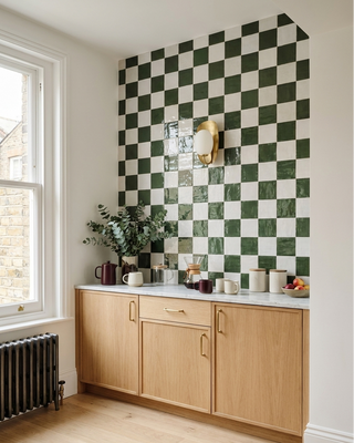 Kitchen with green and white checkered tile backsplash and wooden cabinets.
