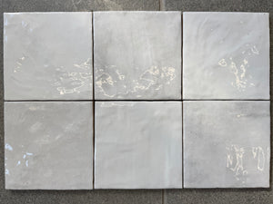 Six gray tiles with marble-like patterns on a stone surface