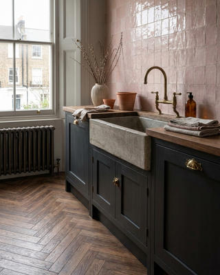 Kitchen with ashdown walnut tile flooring, dark wooden cabinets, a farmhouse sink and pink tiled wall.