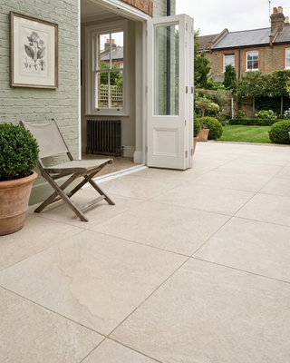 Outdoor patio area with tiled floor, open door and garden view